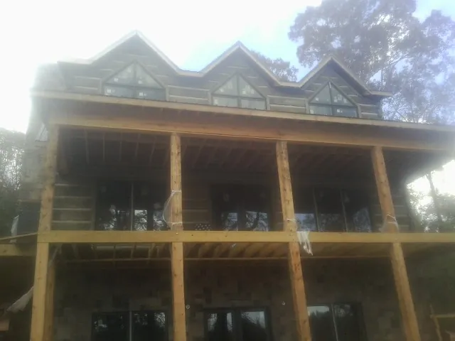 Dormers and porch framing on a large log home under construction — Roof Coating work by our crew in Prairie Grove