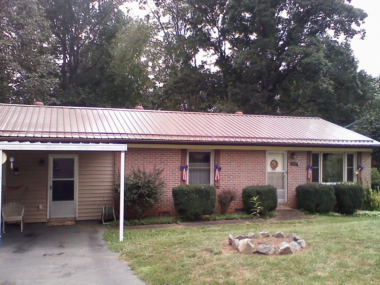 Bronze metal roof and carport on a brick ranch home — Roof Repair work by our crew in Prairie Grove