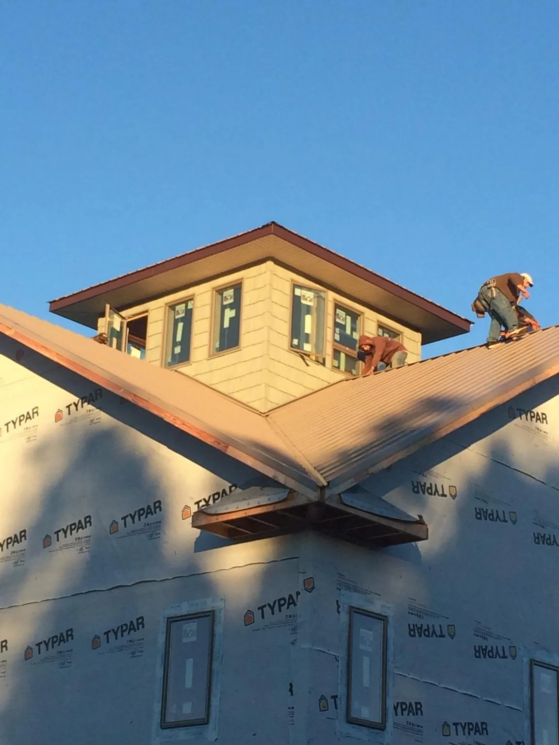 Roofers working around a rooftop cupola on a new metal roof at sunset — Roof Waterproofing in Prairie Grove by Roofing Brothers